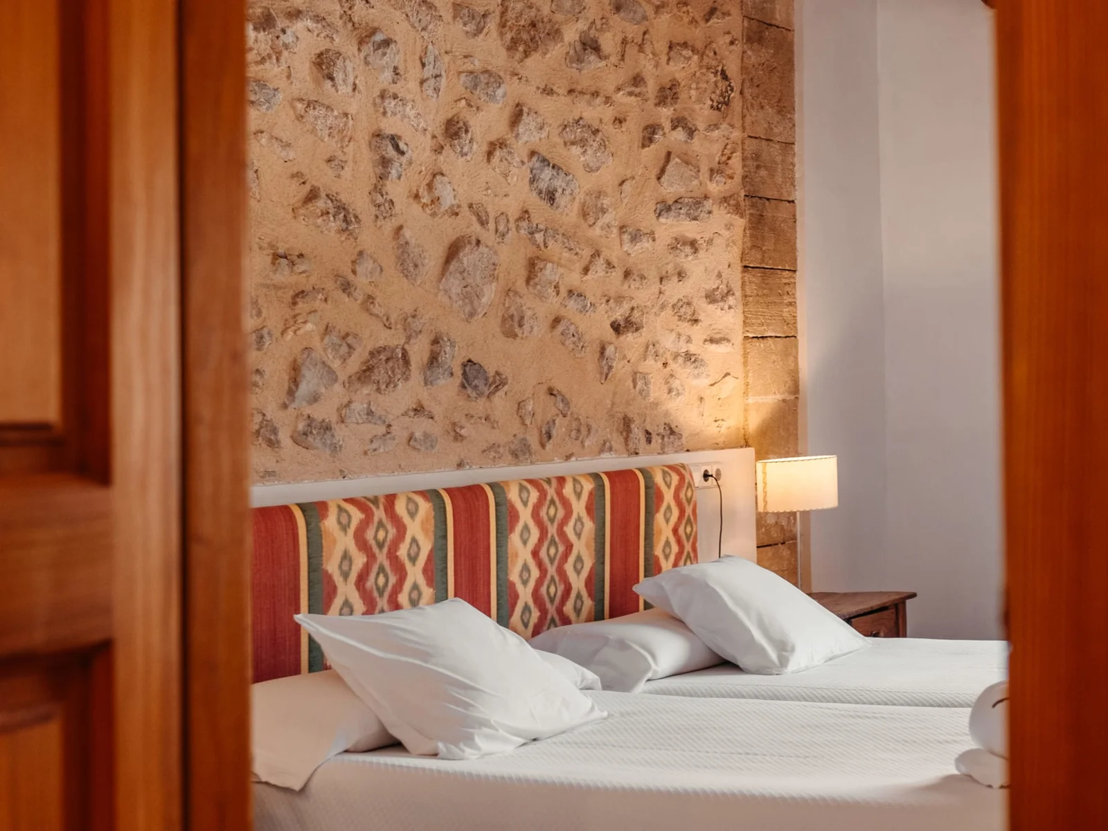Doppelzimmer mit Natursteinwand und Doppelbett